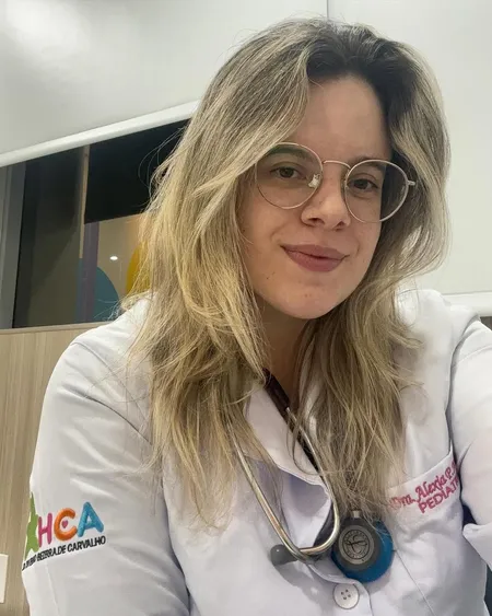 Pediatra Alexia Pinto com jaleco e estetoscópio transmite confiança profissional.